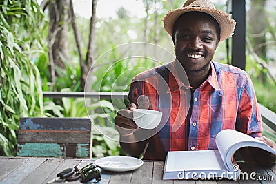 African man reading a book with holding a hot coffee.World book day Concept Stock Photo