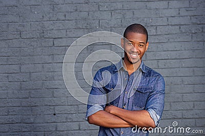 African man smiling against gray wall with blue shirt Stock Photo
