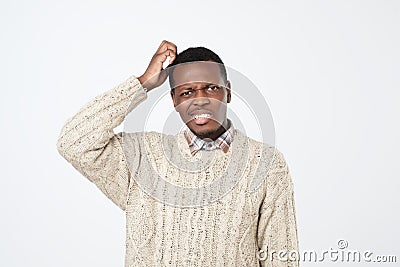 african man in sweater thinking scratching head on white background. How is it supposed to be done concept Stock Photo