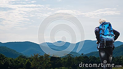 African man traveler views landscape of mountains with evergreens and deep blue sky Stock Photo