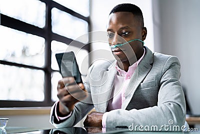 African Man Using Phone With Nasal Oxygen Cannula Stock Photo