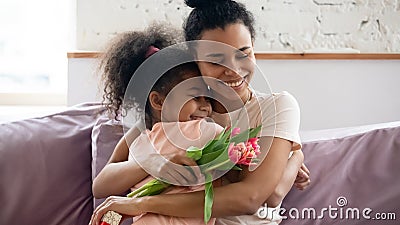 African mom hugs daughter express gratitude for attention and flowers Stock Photo