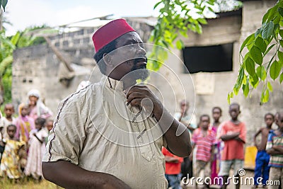 An African Older Man, The Mayor of His Village in Red Muslim Taqiyyah Hat and White Dress. Small Remote Village in Stock Photo