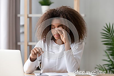 African teen girl rubbing eyes tired from computer holding glasses Stock Photo