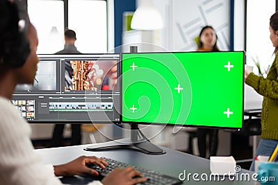 African video editor with headset editing footage using pc with greenscreen Stock Photo