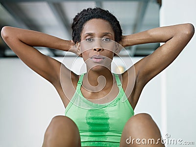 African woman doing series of crunch in gym Stock Photo