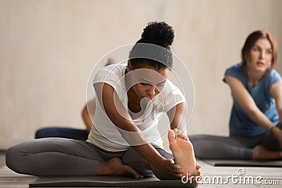 African woman and group of people in Janu Sirsasana pose Stock Photo