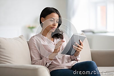 African woman sit on couch using tablet gadget Stock Photo