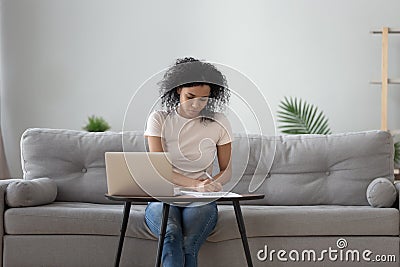 African woman sitting at coffee table holding pen writing Stock Photo