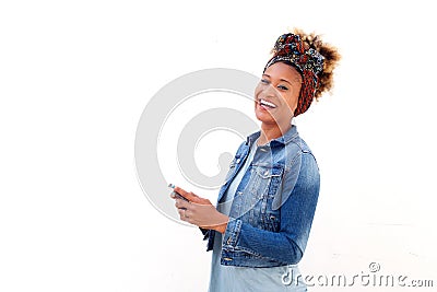 African woman with smart phone standing against white background and laughing Stock Photo