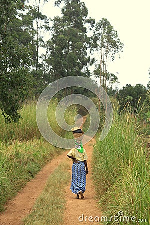 African Woman Walking Carrying Basket on her Head Editorial Stock Photo