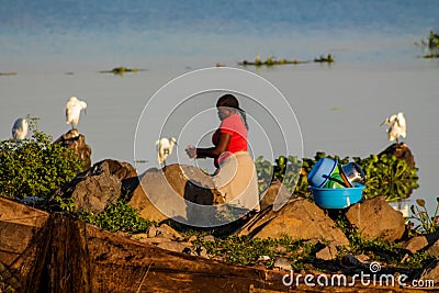 African woman wash dishes on the shore of Lake Victoria Editorial Stock Photo