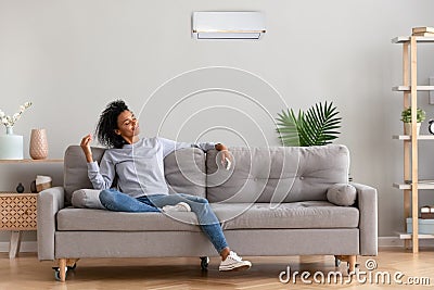 African young relaxed woman sitting on couch breathing fresh air Stock Photo