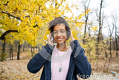 Africanamerican girl listening to music in the autumn park Stock Photo