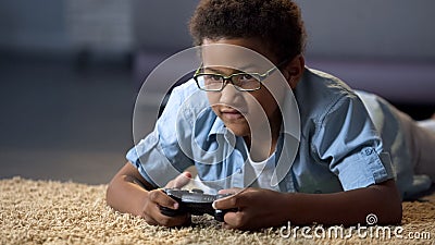 Afro-American boy absorbedly playing on new video game console, home activity Stock Photo