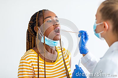 Afro american woman getting oral coronavirus swab test at hospital Stock Photo