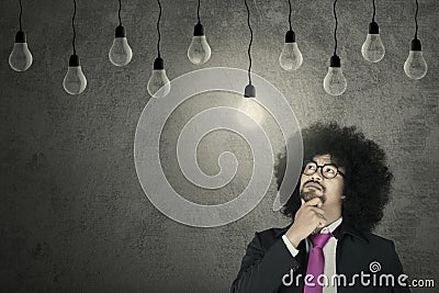 Afro businessman looking at light bulb Stock Photo