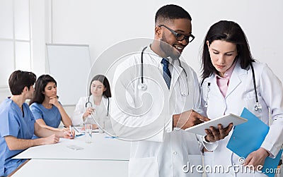 Afro doctor giving advice to his colleague during meeting Stock Photo