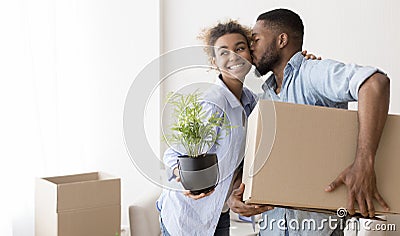 Afro Husband Kissing Wife In Cheek Holding Moving Box Indoor Stock Photo