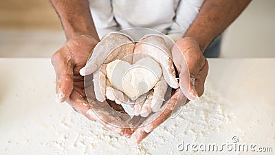 Afro man hands holding child hands with heart shaped pastry Stock Photo