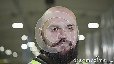 Afsluitend portret van een serieuze kauwglanzende kaukasus met zwarte baard die naar de camera kijkt Werknemer in groen vest stock video Afsluitend portret van een serieuze kauwglanzende kaukasus met zwarte baard die naar de camera kijkt Werknemer in groen vest stock video