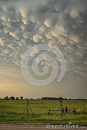 Tripods with equipment belonging to storm chasers below a thundery sky with mammatus clouds on the great plains. Stock Photo