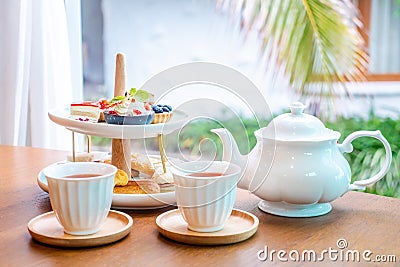 Afternoon tea with fresh cakes, pastries and sandwiches with hot tea Stock Photo