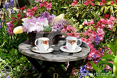Afternoon tea outdoors in spring flower garden with English tea in fancy teacups Stock Photo