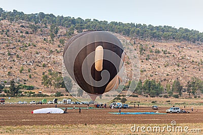 The maintenance team inflates the hot air balloon in the shape of head of a monkey on the ground before the flight at the hot air Editorial Stock Photo