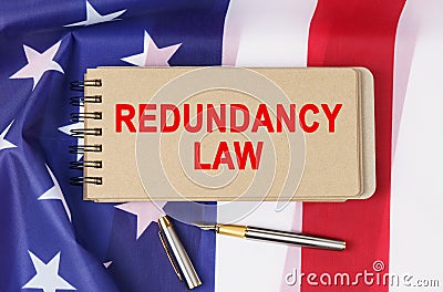Against the background of the flag of the USA lies a notebook with the inscription - REDUNDANCY LAW Stock Photo