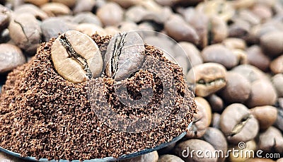 Against the background of roasted aromatic coffee beans lies a metal spoon filled with ground coffee. A drink made from Stock Photo