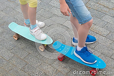 Against the stone paving, close-up, two skateboards with the feet of a boy and a girl on them Stock Photo