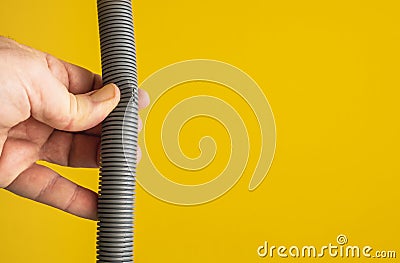 Against the yellow background the hands of a plumber are testing the integrity of a drain pipe: they highlight a crack that caused Stock Photo