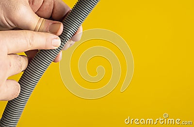 Against the yellow background the hands of a plumber are testing the integrity of a drain pipe: they highlight a crack that caused Stock Photo