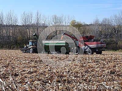 AGCO Challenger MT765D tractor pulling a Killbros 1820 grain cart being loaded from a Massy Ferguson 9540 combine harvester in no Editorial Stock Photo