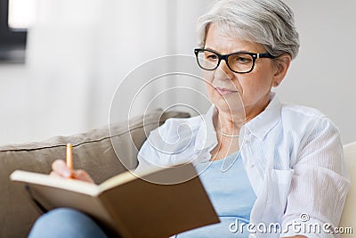 Senior woman writing to notebook or diary at home Stock Photo