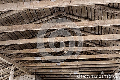 Aged brown wooden timber beam on roof ceiling inside old farm or ranch building interior. Rural gabled roof old Stock Photo