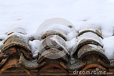 Aged clay roof tiles snowed under winter snow Stock Photo