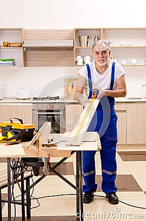 The aged contractor repairman working in the kitchen Stock Photo