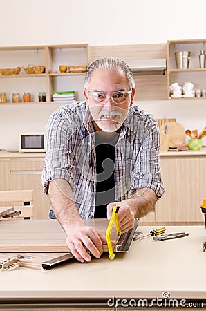 Aged contractor repairman working in the kitchen Stock Photo