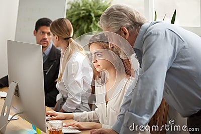 Aged executive manager supervising computer work of intern in of Stock Photo