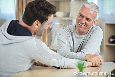 Aged father and handsome son competing in arm wrestling Stock Photo