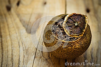 Aged fermented black chinese puer tea in a tangerine peel with lid, weathered wood background, close up Stock Photo