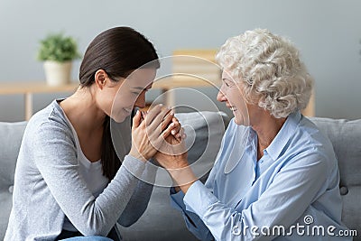 Aged grandmother adult granddaughter laughing seated on sofa enjoy talk Stock Photo