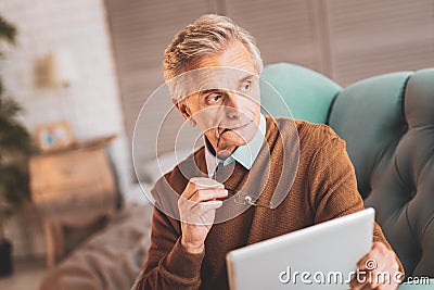 Aged man feeling thoughtful after reading curious news Stock Photo