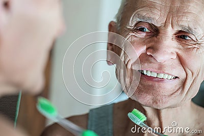 Aged person looking in mirror and having daily denture care Stock Photo