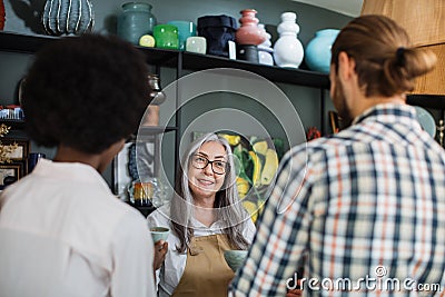 Aged saleswoman consulting multiracial couple at decor store Stock Photo