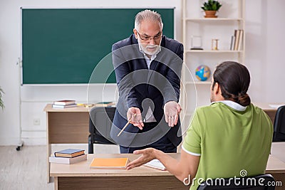 Aged teacher and male lazy student in the classroom Stock Photo