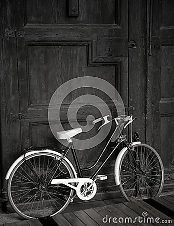 Aged vintage black bicycle, big wooden door, black Stock Photo