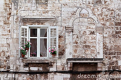 Aged windows and flower boxes of historical building from old town of Pula, Croatia / Detail of ancient venetian architecture. Stock Photo